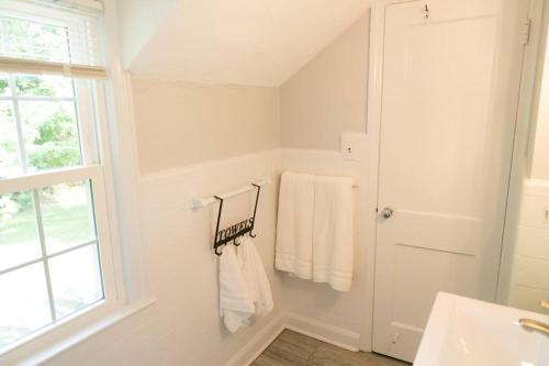 a bathroom with white towels and a sink and a window at Charming & Cozy 3BR home mins to SU-ESF-Upstate-Le Moyne in Syracuse