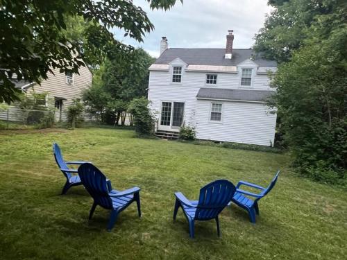 three blue chairs sitting in the grass in front of a house at Charming & Cozy 3BR home mins to SU-ESF-Upstate-Le Moyne in Syracuse