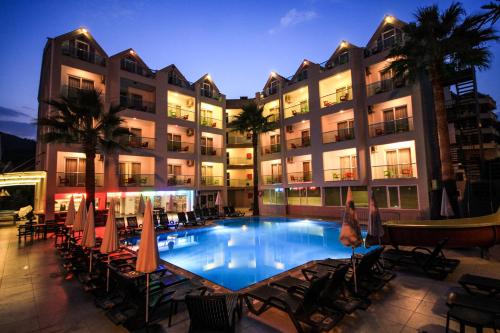 a hotel with a swimming pool with chairs and umbrellas at Palmea Hotel in Marmaris
