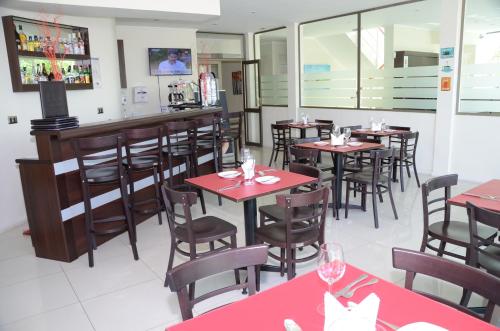 a restaurant with red tables and chairs and a bar at Hotel Del Rio in Constitución