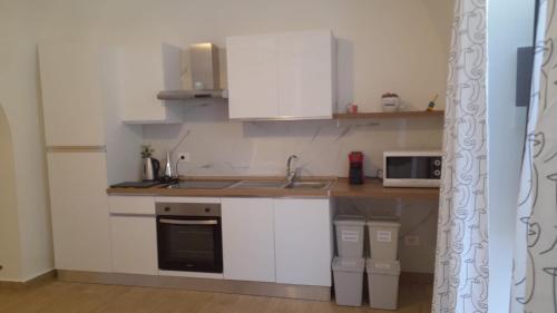 a kitchen with white cabinets and a sink and a microwave at Casa fortino in Catania