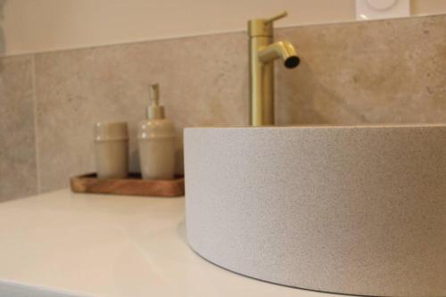 - un évier avec un robinet et 2 bouteilles sur un comptoir dans l'établissement La Cachette du Bonheur, à Cély-en-Bière