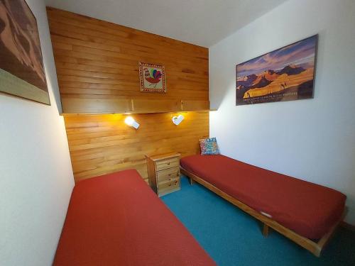 - une chambre avec un lit rouge et un mur en bois dans l'établissement 2 pièces, skis aux pieds, proche commerce et télécabine - FR-1-356-224, à Valmorel