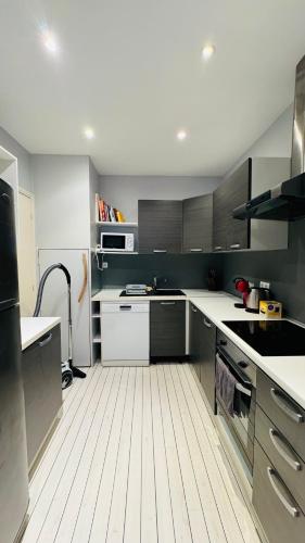 une cuisine avec des comptoirs blancs et des placards gris dans l'établissement Eze flat with terrace sea view and mountain view, à Èze