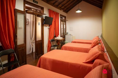 a hotel room with three beds with orange sheets at ALOJAMIENTOS NECANA in Icod de los Vinos