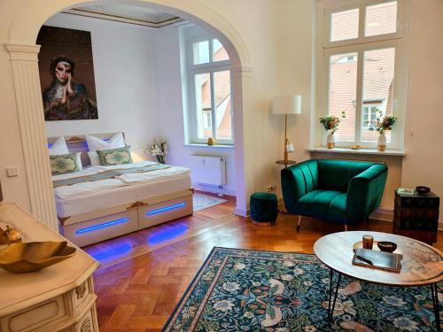 a bedroom with a bed and a green chair at Exklusive Ferienwohnung Agnes in zentraler Bestlage von Zeitz! Vollausgestattet, freie Parkplätze, Magenta-TV, Highspeed WLAN, Fahrstuhl in Zeitz