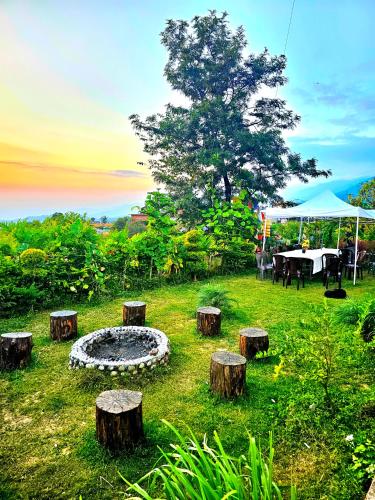 a garden with a fire pit and some logs at Hana Resort Landing Site in Bīr