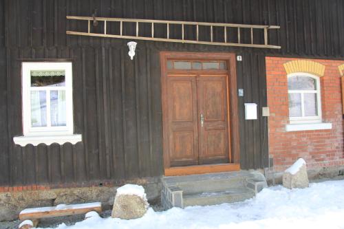 a black house with a wooden door and two windows at Ferienhaus Anno Dazumal, wie zu Oma`s Zeiten in Klingenthal