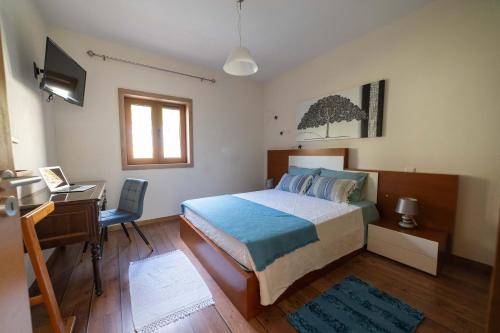 a bedroom with a bed and a desk and a television at Casa do Casal do Douro in Marco de Canavezes