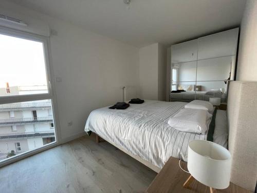 une chambre blanche avec un lit et une grande fenêtre dans l'établissement Appartement belle escale, à Dunkerque