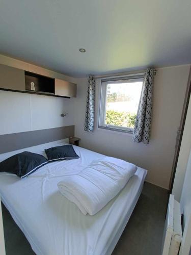 un grand lit blanc dans une chambre avec une fenêtre dans l'établissement Mobil home Luxueux - 40 m2 terrasse couverte - La Palmyre Les Mathes - Les Charmettes 4 étoiles, aux Mathes
