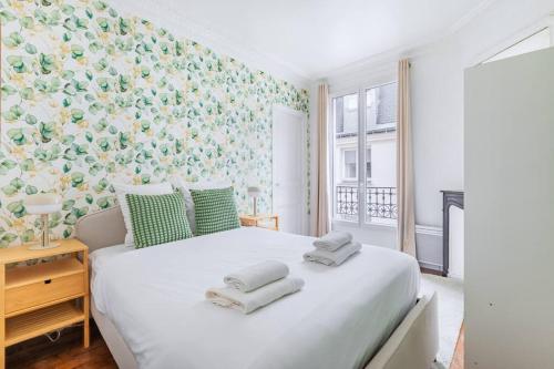 une chambre avec un grand lit blanc avec des serviettes dessus dans l'établissement Appartement Coloré et Lumineux à Paris, à Paris