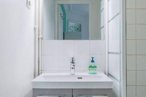une salle de bain avec un lavabo blanc et un miroir dans l'établissement Appartement Coloré et Lumineux à Paris, à Paris