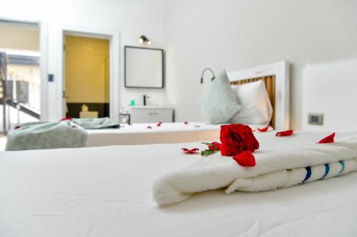 a white bed with a towel with a rose on it at Honky Tonk Colonial in Santo Domingo