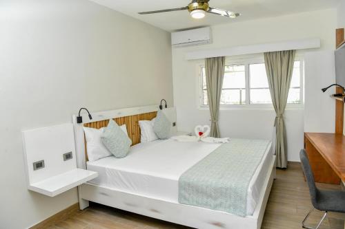 a bedroom with a white bed and a window at Honky Tonk Colonial in Santo Domingo