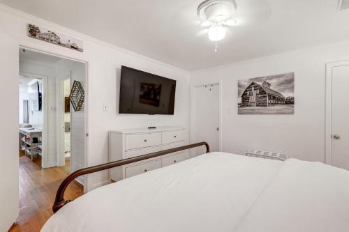 a white bedroom with a bed and a flat screen tv at Family-Friendly Knoxville Home Close to UT! in Knoxville