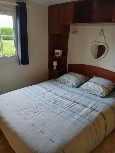 une chambre avec un lit avec une couette bleue et une fenêtre dans l'établissement Bungalow charmant à Meschers-sur-Gironde avec piscine partagée, à Meschers-sur-Gironde