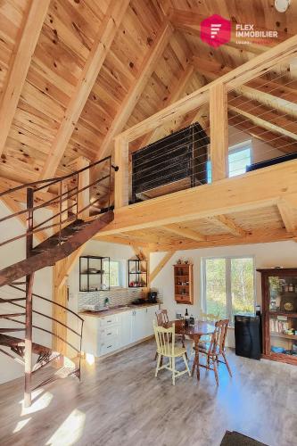 a kitchen and dining room with a spiral staircase in a house at L'Ermite - Rustique Écoresponsable Dans la nature in Notre-Dame-Des-Bois