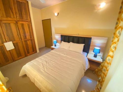 una camera da letto con un letto bianco e due lampade di BelleVille Residence a Bobo-Dioulasso