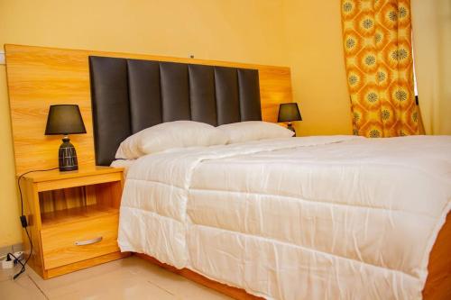 una camera con un grande letto e un comodino con due lampade di BelleVille Residence a Bobo-Dioulasso