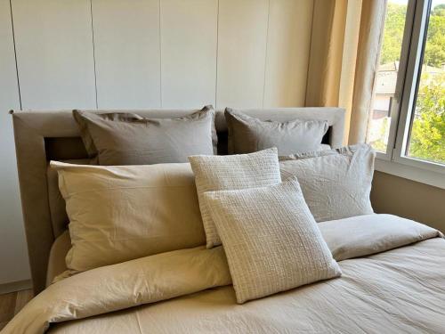 une pile d'oreillers sur un lit avec une fenêtre dans l'établissement Appartement Cannes cosy vue mer, à Cannes