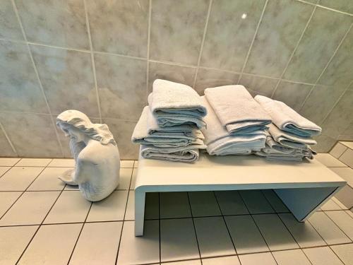 a pile of towels sitting on a bench in a bathroom at Wolkenzimmer mit 140 cm Bett im Erdgeschoss in Seligenstadt