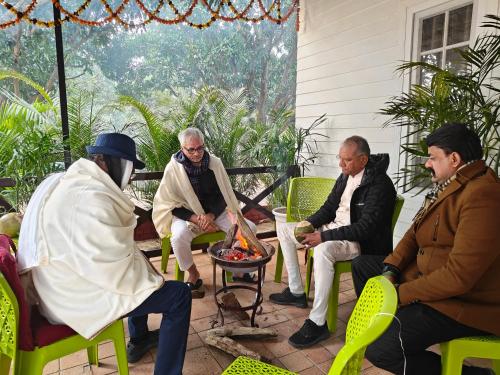 a group of men sitting around a fire pit on a patio at Shobhayan inn, airport railway station pickup free in Ayodhya