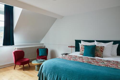 a bedroom with a bed and two chairs at La Closerie des Capucines in Arbois