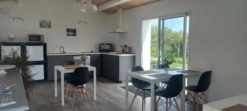une cuisine avec des tables et des chaises blanches ainsi qu'une cuisine avec une fenêtre dans l'établissement Horizons de L'Ile, à L'Ile d'Yeu