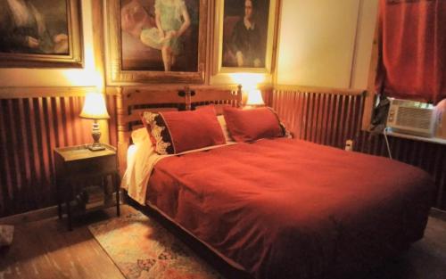 a bedroom with a bed with a red blanket and two lamps at La Loma del Chivo Llc - The Spirit room in Marathon