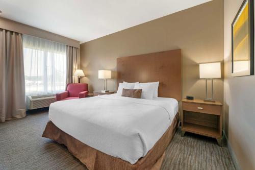 ein Hotelzimmer mit einem großen Bett und einem roten Stuhl in der Unterkunft Best Western Plus Jefferson in Jefferson