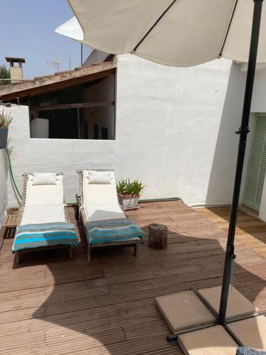 two lounge chairs and an umbrella on a deck at Beach House Mallorca in Cala Pi
