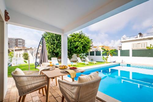 a patio with a table and chairs next to a swimming pool at Urban Bliss Guesthouse II in Faro