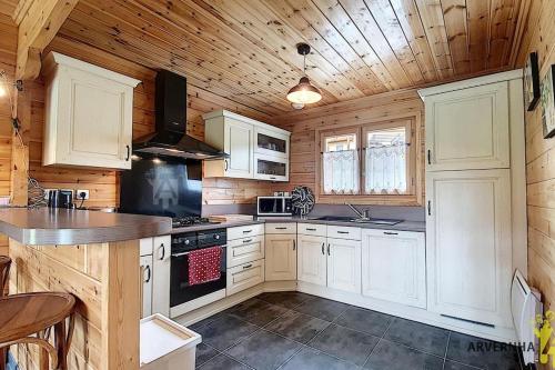 une cuisine avec des armoires blanches et un plafond en bois dans l'établissement Chalet Lorine, à Saint-Pierre-Colamine