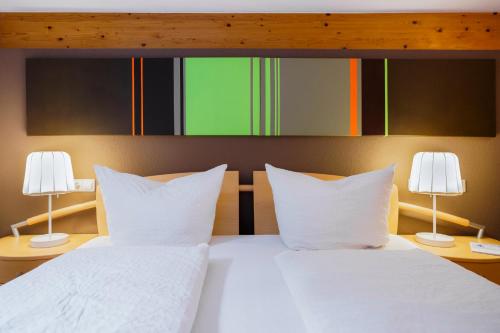 a bedroom with two beds with white sheets and two lamps at Haus Röcken in Dalaas