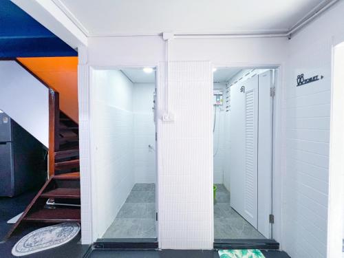 a hallway with white tile walls and a staircase at Sleep like a baby Hostel Pattaya in Jomtien Beach