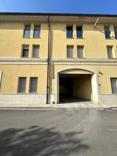 a large yellow building with a parking garage at Appartamento Loreto-Fiera in Cremona