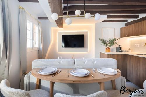 une salle à manger avec une table et un canapé blanc dans l'établissement SUPER CENTRAL - Marais Designer One-Bedroom - FREE Parking, à Paris