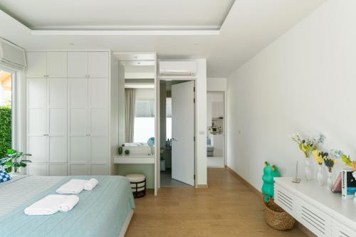 a white bedroom with a bed and a bathroom at Friendly Kamala Garden View in Kamala Beach