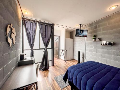 a bedroom with a blue bed and some windows at Casa Cobre StayHouse in San Luis Potosí