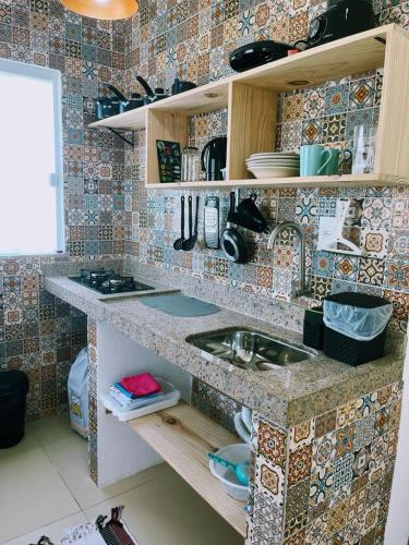 a kitchen with a sink and a tiled wall at Ilha de Boipeba kitnets para temporada - Morada dos Pássaros Boipeba in Ilha de Boipeba