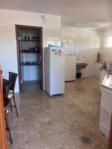 a kitchen with a white refrigerator in a room at Casa do Deck Inesquecível - Escarpas do Lago in Capitólio