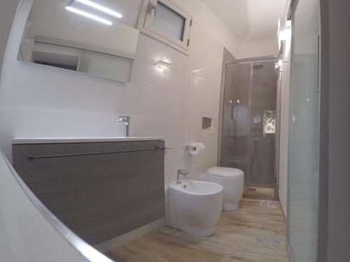 a white bathroom with a toilet and a shower at Al Borgo dell'Arte Suite in Scicli