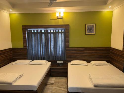 two beds in a room with green walls at Om Sai Villa Guesthouse in Kolkata