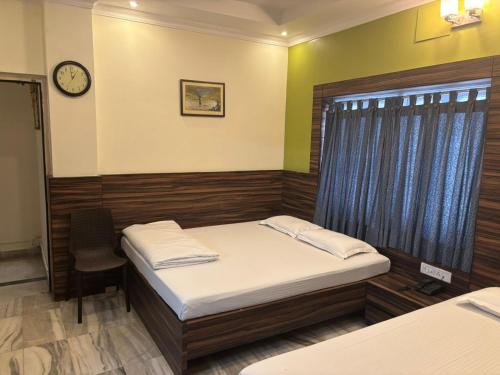 a bedroom with two beds and a clock on the wall at Om Sai Villa Guesthouse in Kolkata