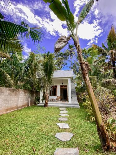 a garden with a pathway leading to a house at The Palm Private Cottages Midigama in Midigama