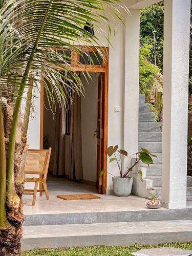 a porch of a house with a palm tree at The Palm Private Cottages Midigama in Midigama