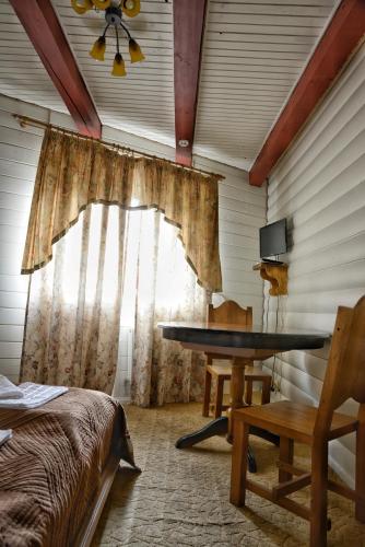 a bedroom with a table and a window with a ceiling at Gotel Milenium in Mykulychyn