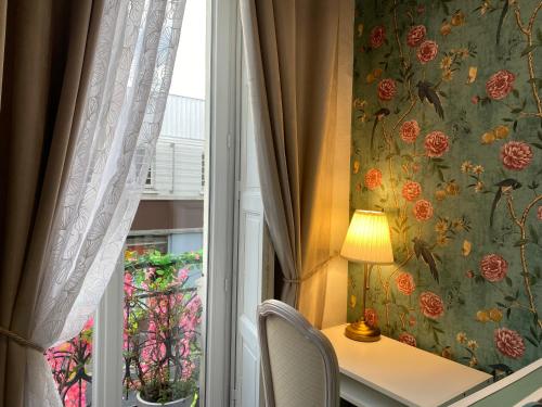a window with a table and a lamp next to a curtain at Hotel Saint Yves in Nantes