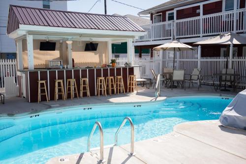 a swimming pool with chairs and a house at The Burgundy Inn Hotel and Apartments in Ocean City